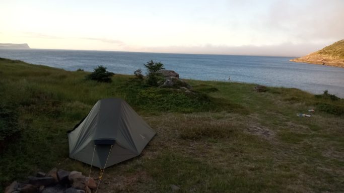 Wasserdichte, leichte und robuste Zelte Ein Zelt steht auf einer Wiese mit Blick auf das Meer und Hügel im Hintergrund.